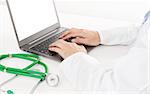 Close up of doctor using laptop in front of stethoscope at desk