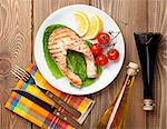 Grilled salmon, salad and condiments on wooden table. Top view