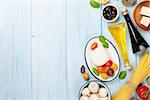 Mozzarella, tomatoes, basil and olive oil on wooden table. Top view with copy space