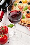 Pizza and red wine on wooden table background