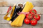 Pasta, tomatoes, condiments and spices on wooden table background