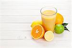 Orange juice and citrus fruits on white wooden table with copy space