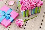 Valentines day card with gift box full of pink roses over wooden table