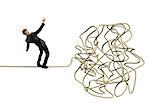 Businessman balancing attempts to get to tangle