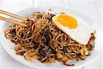 Close-up stir fried char kuey teow with chopstick over wooden background.