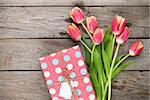 Colorful tulips and gift box on wooden table. Top view with copy space