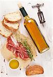 Prosciutto, wine, ciabatta, parmesan and olive oil on wooden table. Top view