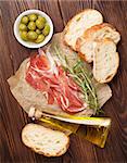 Bruschetta ingredients - prosciutto, olives and olive oil. Top view on wooden table