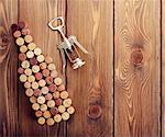 Wine bottle shaped corks and corkscrew over rustic wooden table background. View from above with copy space