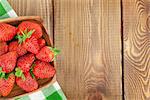 Fresh ripe strawberry in bowl over wooden table background. Top view with copy space