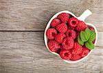 Fresh ripe raspberries bowl on wooden table background with copy space