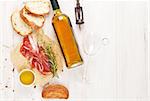 Prosciutto, wine, ciabatta, parmesan and olive oil on wooden table. Top view with copy space