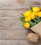 Yellow tulips bouquet over wooden table background with copy space