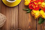 Colorful tulips bouquet and coffee cup on wooden table. Top view with copy space