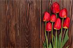 Red tulips bouquet over wooden table background with copy space