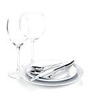 Silverware or flatware set over plates and wine glasses. Isolated on white background
