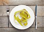 Plate with measure tape, knife and fork. Diet food on wooden table
