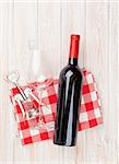 Red wine bottle, glass and corkscrew on white wooden table background. Top view with copy space