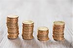 Coins stack in row on wooden background, financial concept. Focus on foreground with blur background.