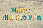 The colorful words "HAPPY THANKSGIVING" made with wooden letters on old wooden plank.