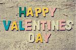 The colorful words "HAPPY VALENTINES DAY" made with wooden letters on old wooden board.