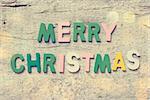 The colorful words "MERRY CHRISTMAS" made with wooden letters on old wooden board.