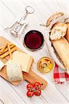 White and red wine, cheese and bread on white wooden table