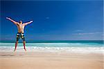 Athletic young man enjoying the summer, jumping in a tropical beach