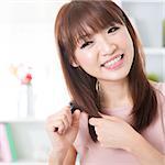 Portrait of attractive Asian girl combing hair in the morning. Young woman indoors living lifestyle at home.