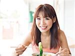 Asian girl eating vegetable noodles at Chinese restaurant. Young woman living lifestyle.