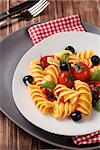 Italian pasta with cherry tomatoes, black olives and basil.