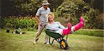 Happy senior couple playing with a wheelbarrow in a sunny day