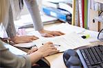 Cropped shot of two businesswomen checking paperwork at office desk