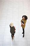 High angle view of two businesswomen chatting in office atrium