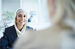 Over shoulder view of young businesswoman chatting to colleague in office