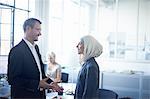 Mature businessman talking to young businesswoman in office