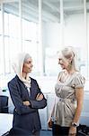 Young and mature businesswomen chatting in office