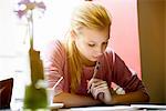 Young woman writing in note book at cafe table