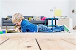 Boy playing with digital tablet on wooden floor