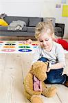 Girl playing with teddy bear at home