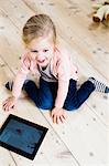 Girl using digital tablet on wooden floor