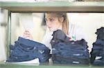 Woman behind shelves of jeans in laundry