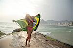 Young woman holding up Brazilian flag,  Ipanema beach, Rio De Janeiro, Brazil