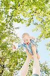 Baby boy balancing on top of mothers feet under blue sky