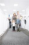 Portrait of family with two children browsing washing machines in electronics store