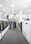 Male shopper and son checking prices on digital tablet in electronics store