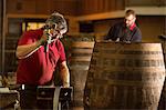 Male cooper using hammer in cooperage with whisky casks