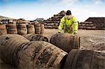 Young man rolling whisky cask at cooperage