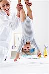 Paediatrician holding baby boy upside-down