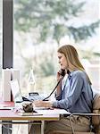 Young businesswoman talking on telephone at home desk